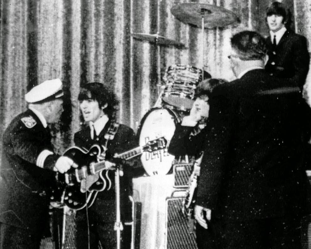 Police Inspector Carl Bear of Cleveland's Juvenile Bureau orders George Harrison and the other members of the Beatles off the stage of the Public hall in Cleveland, Ohio, as teenagers rushed the stage, 1964.