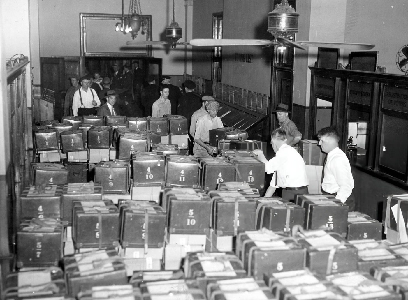 Election officials, police officers, and truck drivers gather at the Election Department in City Hall Annex, where ballots are ready to go out to polling places, 1946.