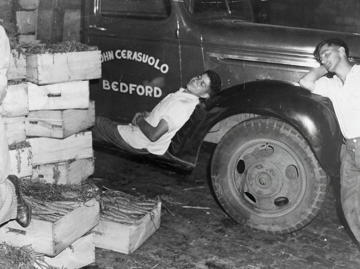 A man sleeps on the side of a truck at the Faneuil Hall Market in Boston, 1940.