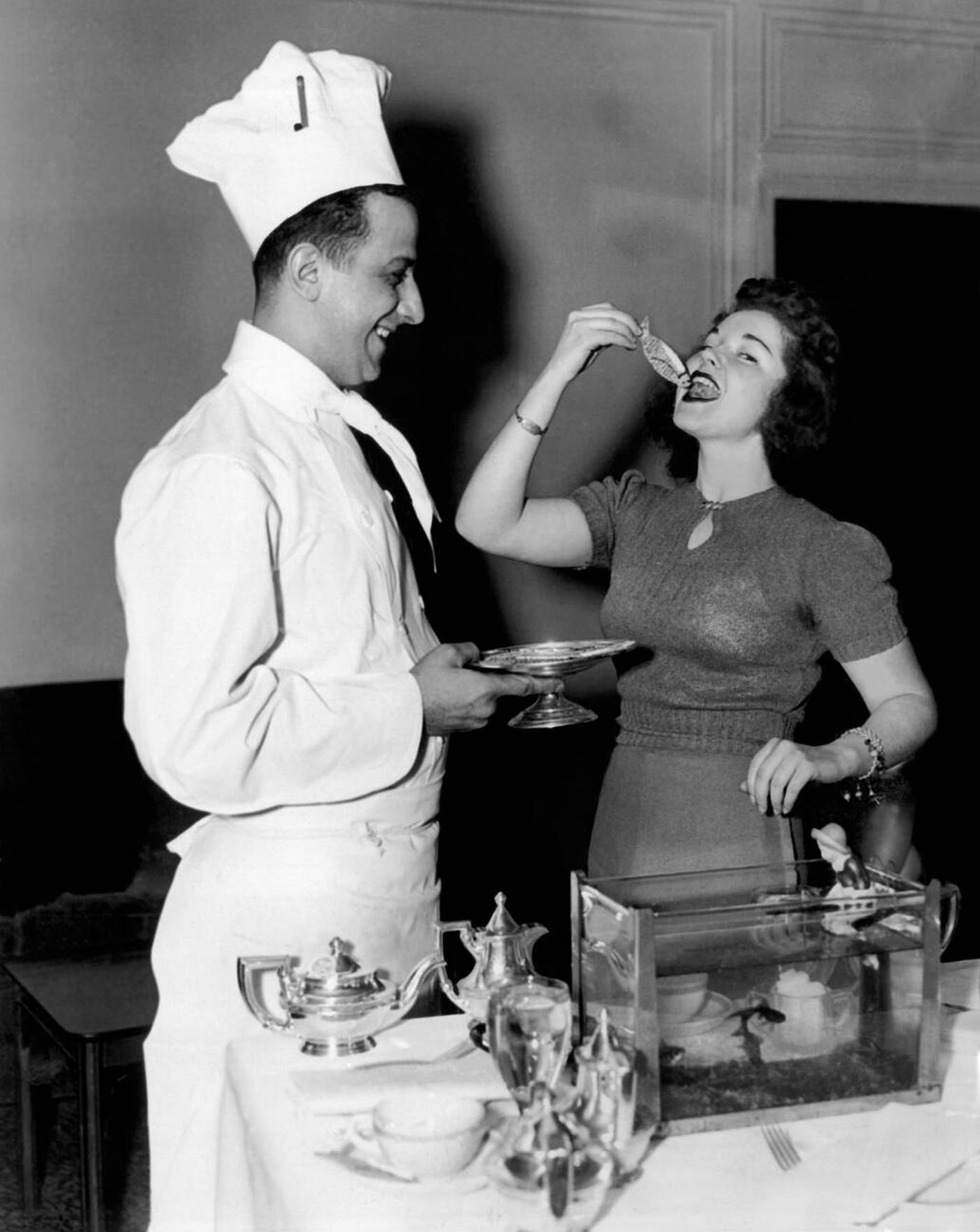 A Kappa Kappa Gamma sorority member at Boston University tries eating a goldfish made of cake at the Statler Hotel, 1939.