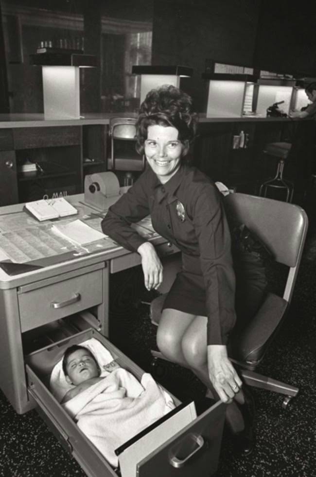 A Los Angeles Police Officer looks after an abandoned baby in the drawer of her desk, 1971.