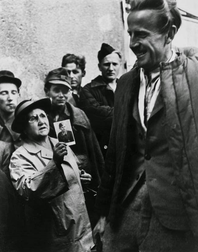 A mother shows a picture of her son to returning prisoners of war in an attempt to find him, Vienna, 1947.
