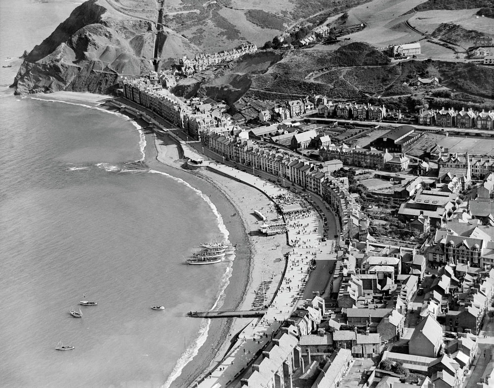General view of Aberystwyth showing seafront and town in summer, The dignified seafront of Aberystwyth is captured here in the summer of 1932, with pleasure boats moored on the beach ready to take holidaymakers on trips around Cardigan Bay.