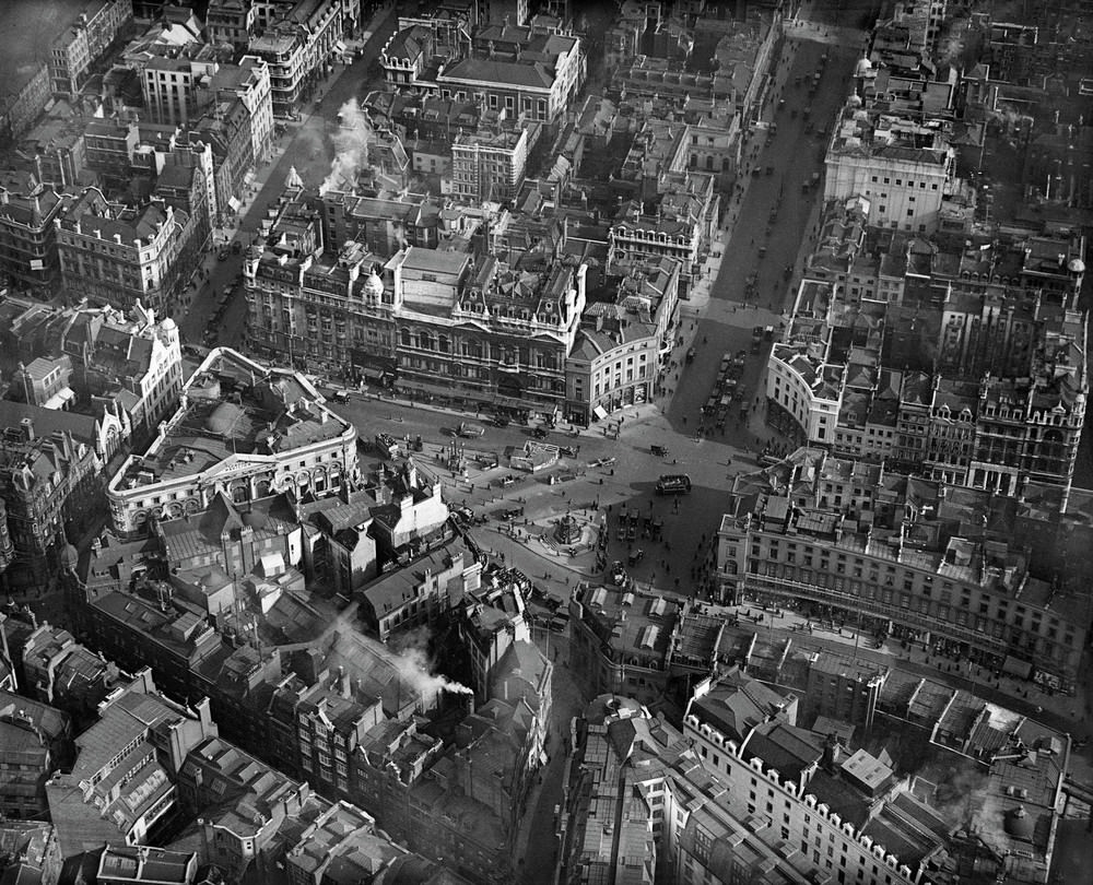 Piccadilly Circus, Westminster. Pictured here in March 1921 – before the installation of any traffic lights – Piccadilly Circus is a busy throng of pedestrians, horsedrawn carriages, omnibuses and motorcars, all revolving around the aluminium-cast statue of Eros.