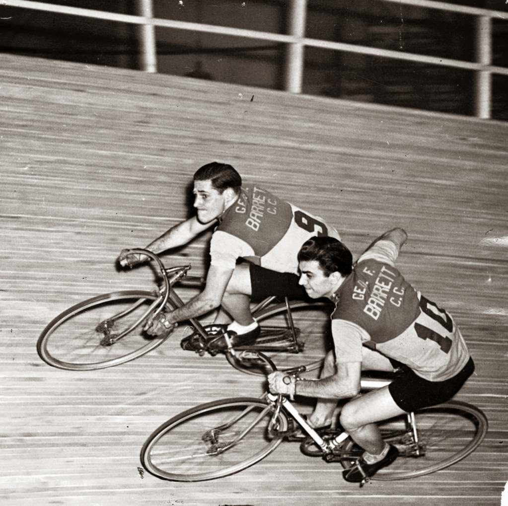Bill Jacoby and Ed Carfagnini, a team of Chicago's youngsters, maintain their equilibrium during a six-day bicycle race at the Coliseum; Carfagnini is giving Jacoby a push as the latter takes over for the team, 1942.