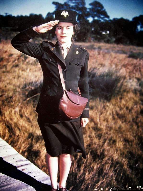 A WAC officer wearing the winter duty uniform, stands in salute. This relpaces the first uniform authorized for the WACs: the major change being removal of the belt. The chocolate brown shoulder bag, brown leather gloves and shoes are the authorized accessories.