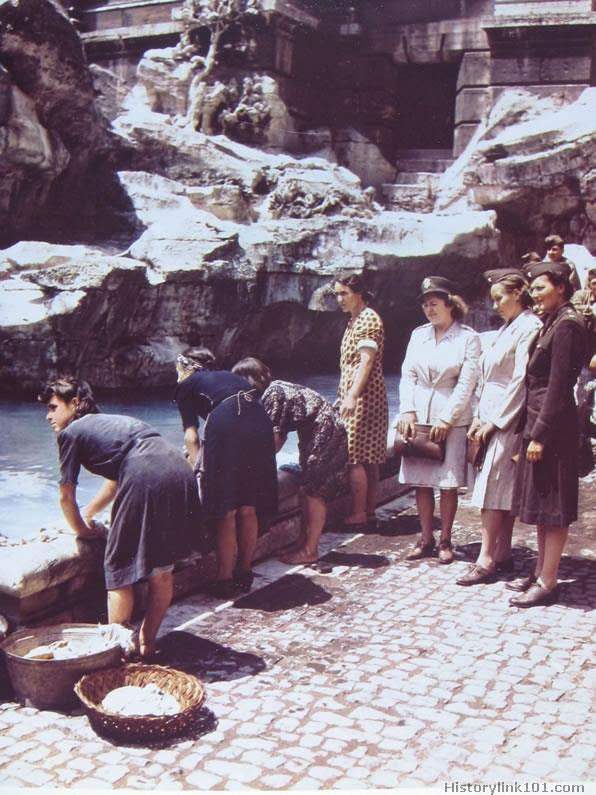 Italian women wash clothes at the fountain of Fontana Verdi while US Army nurses and GI's look on. June 1944.