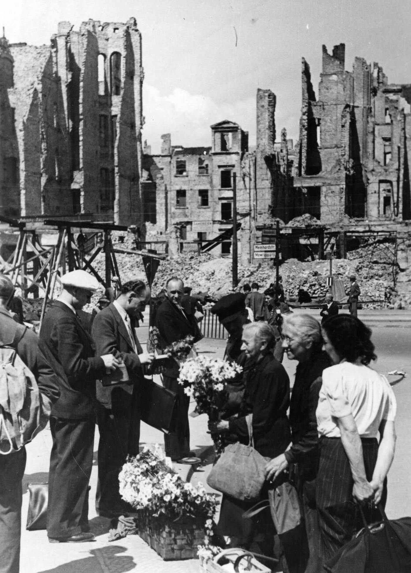 Women sell flowers in front of the ruins of houses on Memhardstrasse street near Alexanderplatz in Berlin, 1945.