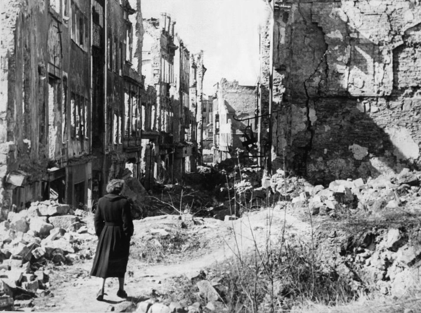 A woman walks down a street in Dresden after the war.