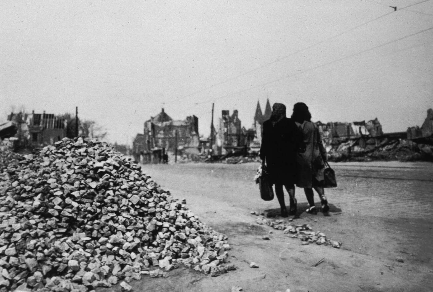 Two German women walk in the ruins of the city of Essen after the Allied forces bombing, 1940s.