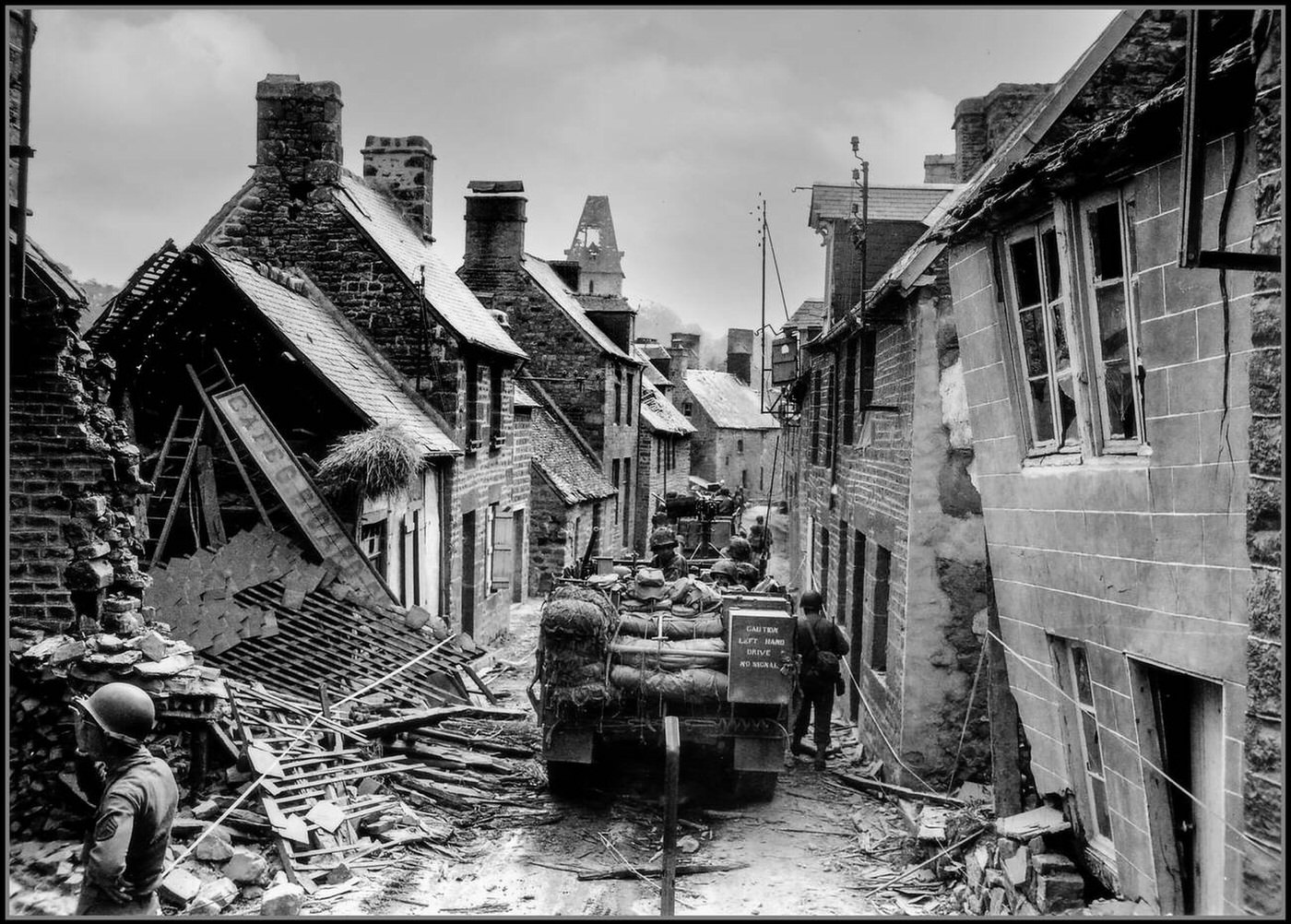 American M2 Half-Tracks slowly traverse the ruined rue Saint Michel in Lonlay L'Abbaye after fierce battles with occupying forces of Nazi Germany after the initial assault on D-Day, 1944.