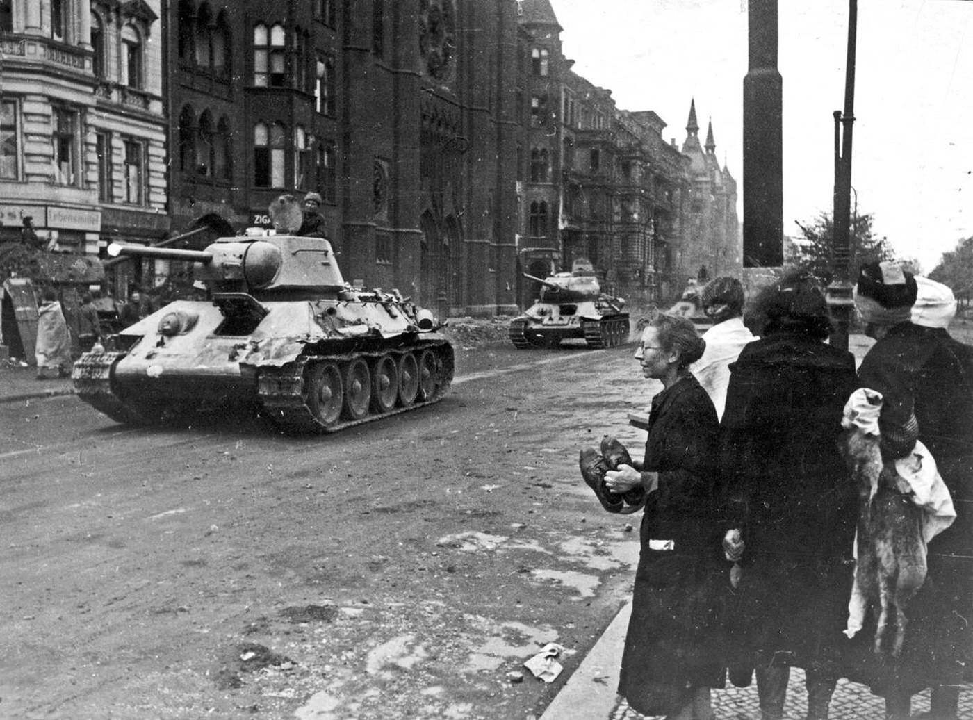 Russian tanks enter a ruined Berlin watched by a group of women, 1945.