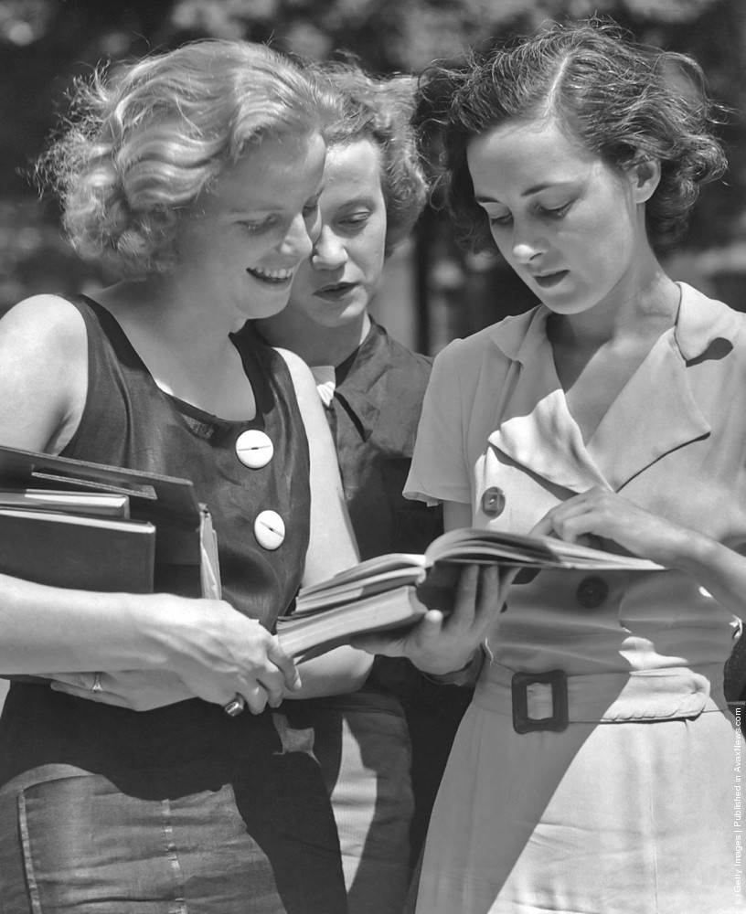 Three female students reading a book, 1950s.