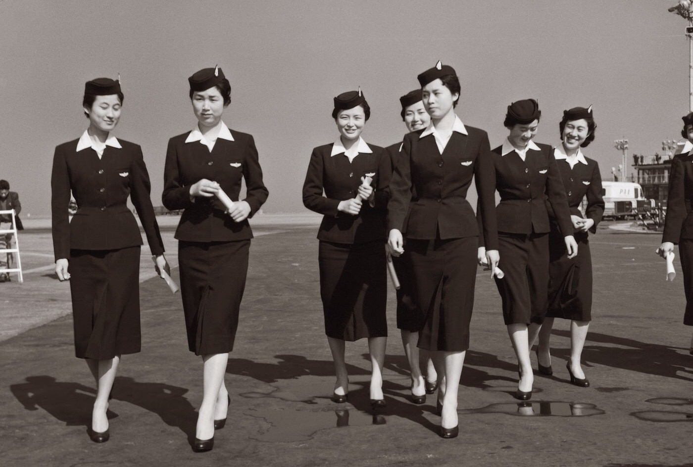 Japan Airlines stewardesses dressed in navy suits, c.1958, designed by Mohei Ito. In 1960, Ito shortened the skirts to just above the knee and added gold buttons.