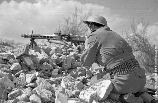A Greek soldier keeps his machine gun at the ready, on the lookout for guerrilla troops during the Greek Civil War, 1948.