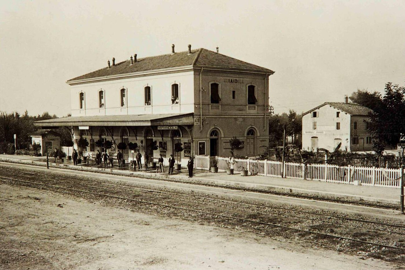 People waiting on a train at Cividale train station in Mirandola Italy, 1930.