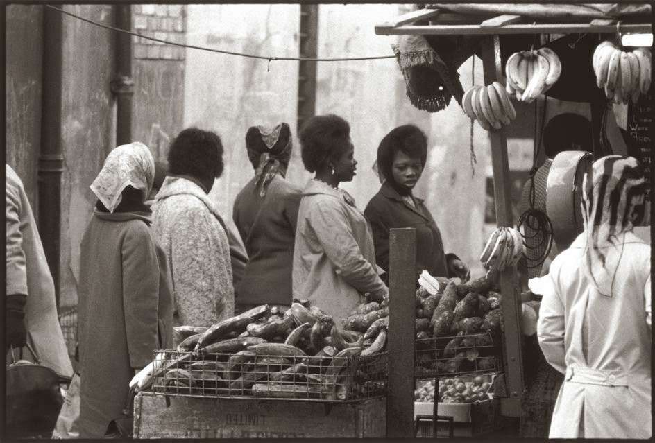 West African women shop for fruits and vegetables in Brixton market, London.
