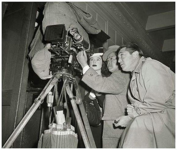 James Wong Howe working his cinemagraphic excellence on the film noir "Nora Prentiss" during February, 1946. Actress, Barbara London, and Director, Vincent Sherman, take an interest in James' viewfinder composition.