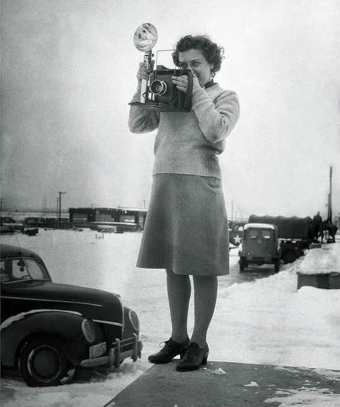 United States Army Photographer lass using the sports finder frame of her Graflex camera.