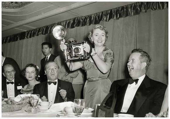 Margaret Truman, daughter of the former President, Harry S. Truman, displays her skills with a Graflex camera. She borrowed the camera from pressmen during a function at the Conrad Hilton in Chicago, Illinois, during September 1953.