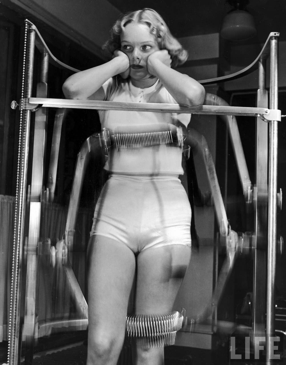 Model Pat Ogden at slenderizing salon enduring the rigors of the Slendo Massager that runs rollers up-and-down to electrically rub away stomach, hips and thighs.