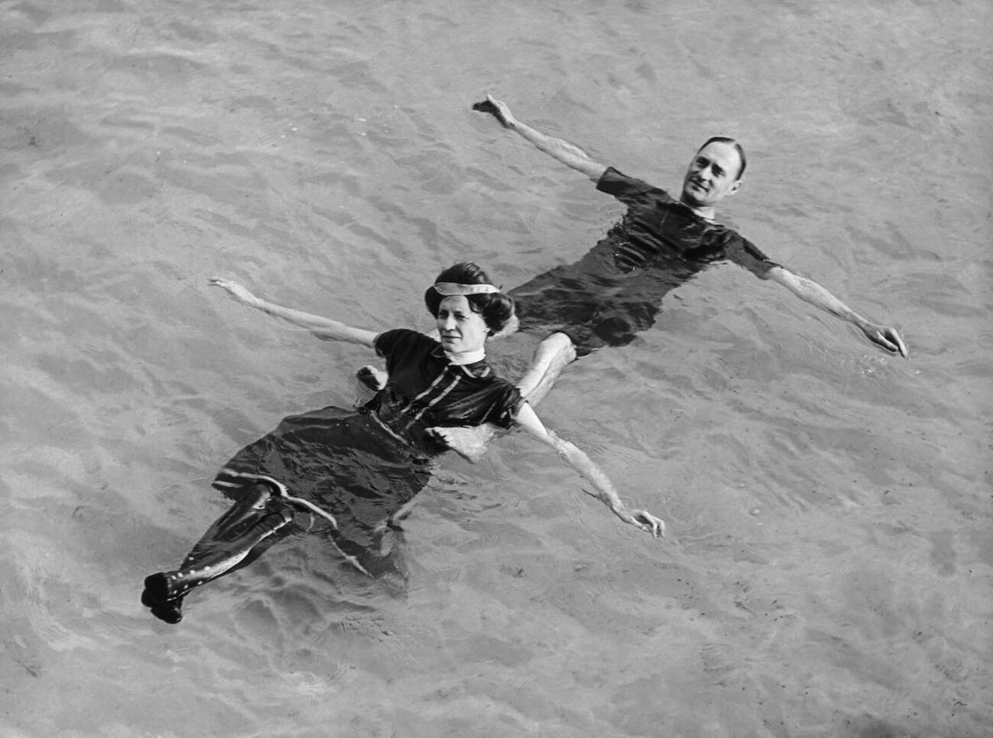 Man and woman floating on their backs in water, 1900s.