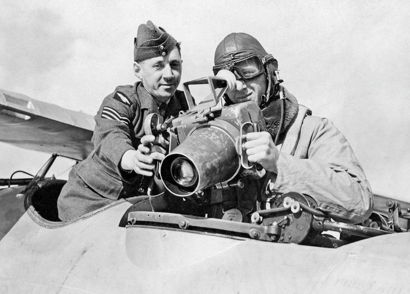 A crewmember of a military airplane with a soldier at a camera mounted on the airplane in England, 1939.