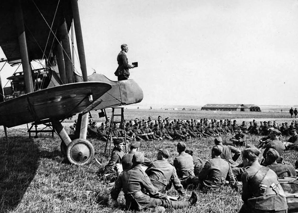 A Sunday morning service in an aerodrome in France with the Chaplain conducting the service from an aeroplane.