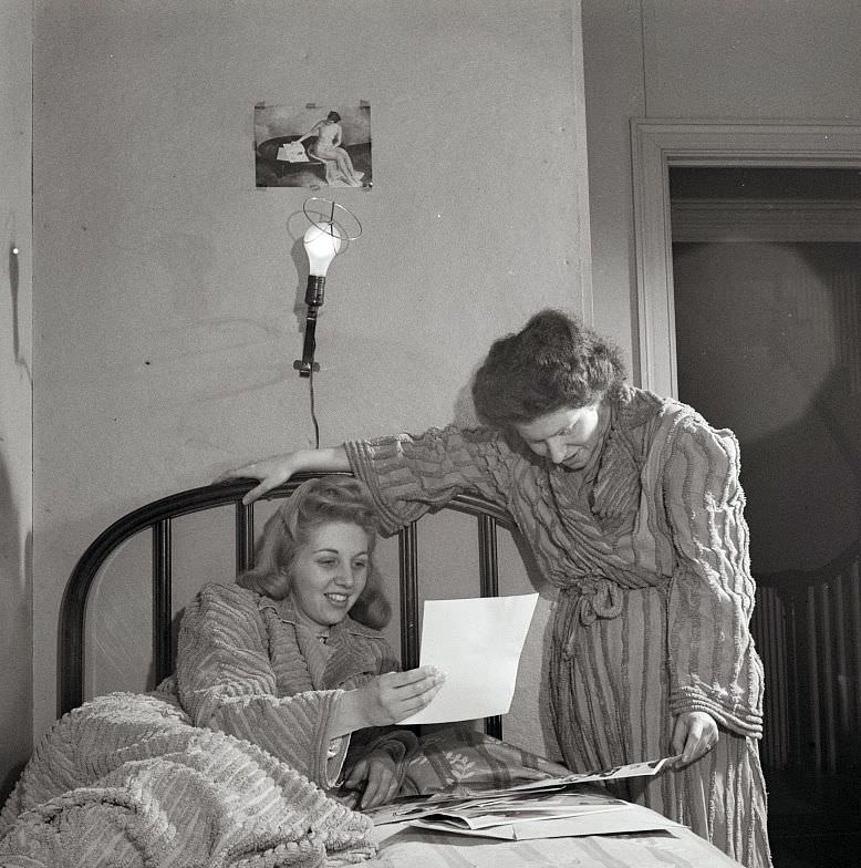 Two girls looking at pictures in their room in a boardinghouse