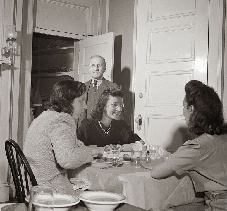 The proprieter of this boardinghouse watches the service at dinner