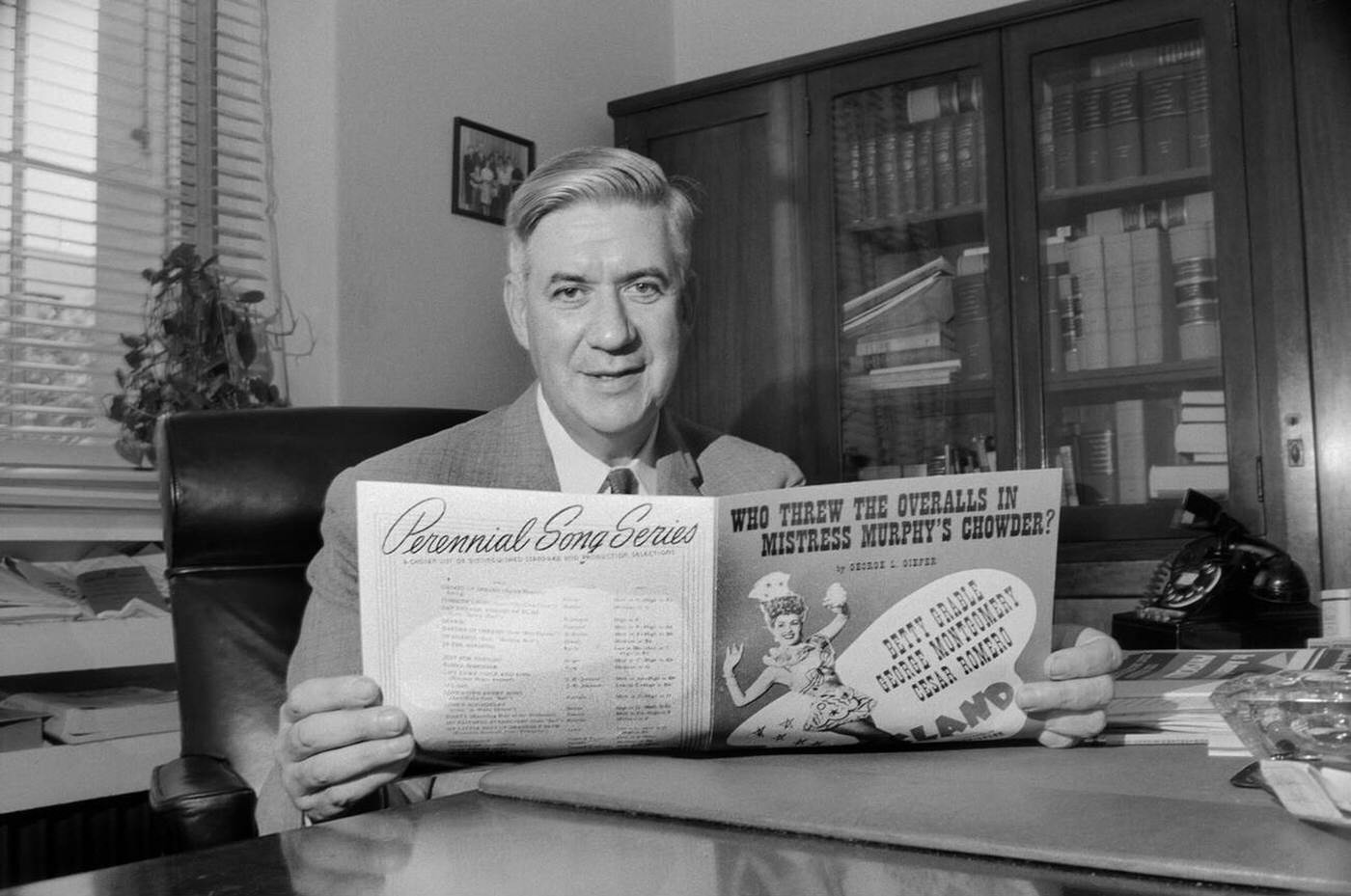 Massachusetts Congressman Thomas P. "Tip" O'Neill sitting at Office Desk and holding Sheet Music, Washington, D.C., 1957.