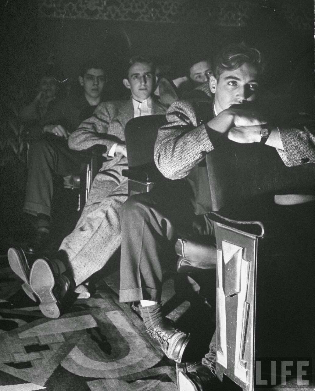 The local movie theater, boys have a very difficult time finding a place to put their long legs.