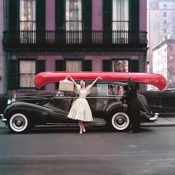Barbara Mullen poses with her arms wide and mouth open in front of a black Rolls-Royce, New York, 1950s