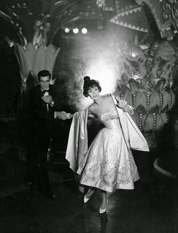 Wearing a creamy white satin dress embroidered with blue and coral beads by Pierre Balmain, 1957