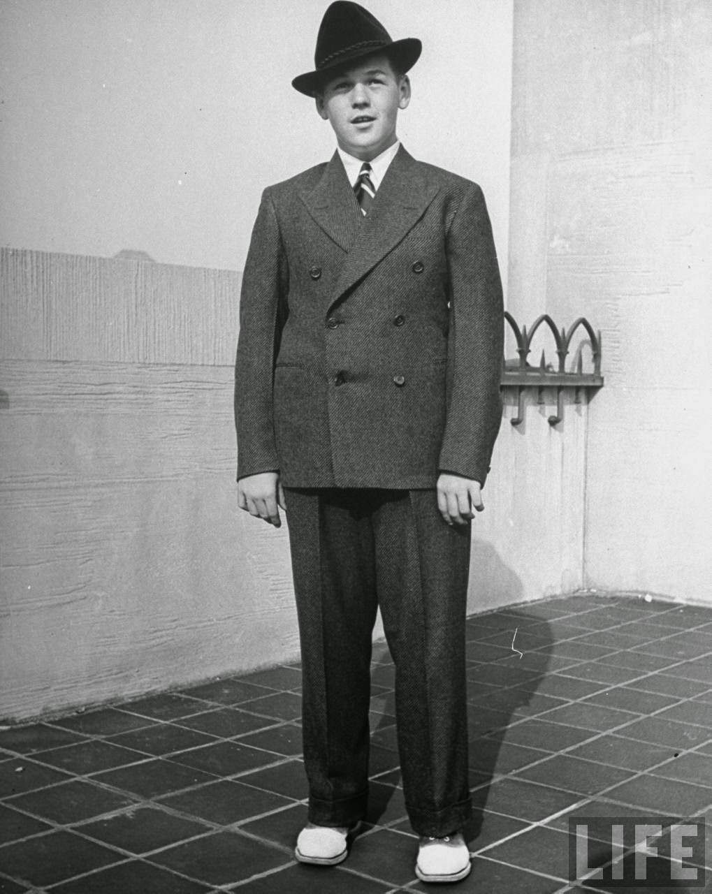 Easy fitting suit, double-breasted, produces a flattering square line on husky boy. Hat with a turned down brim helps the face.