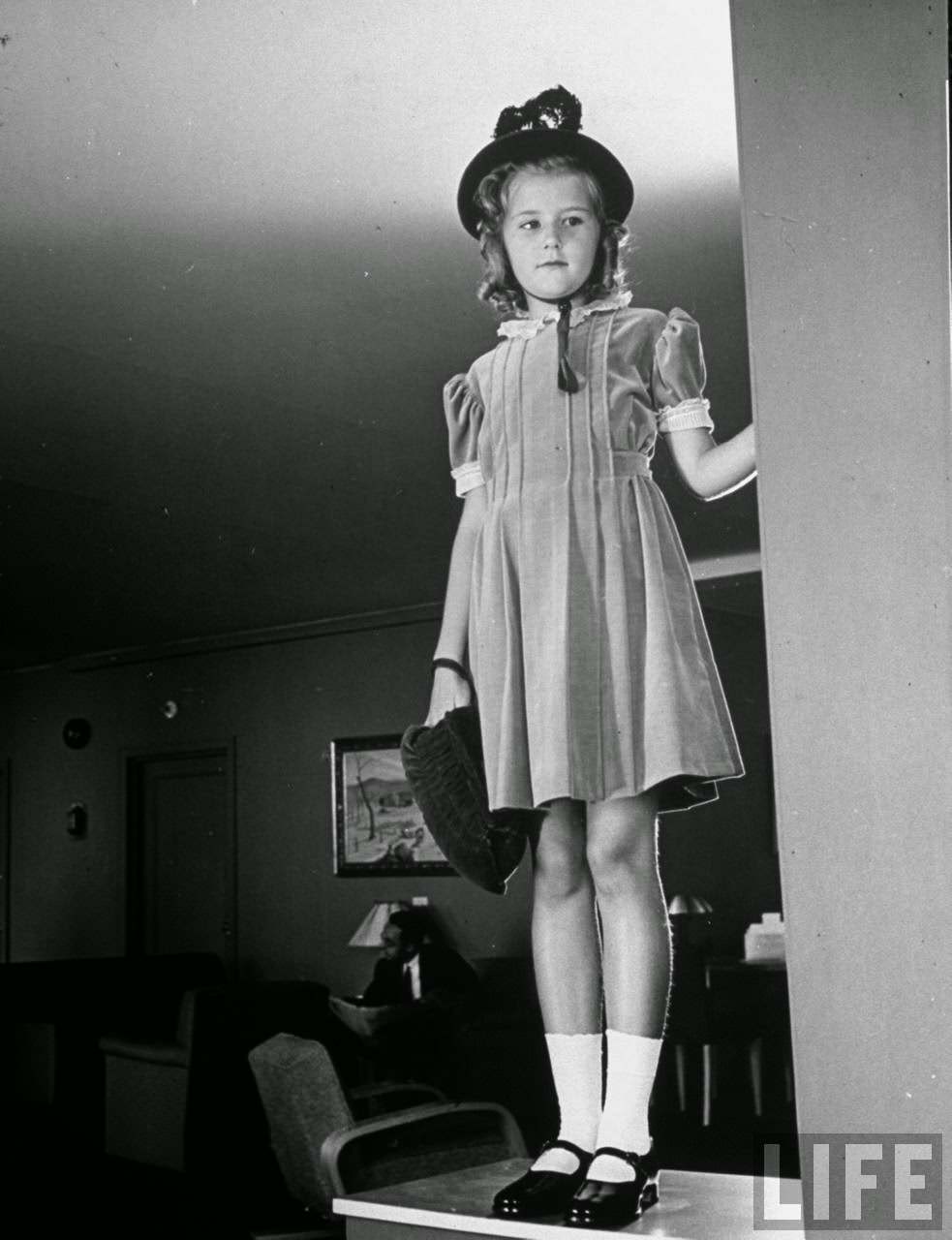 Party dress of rose velveteen, feathered bonnet and a matching bag, make this young girl a perfect little lady.