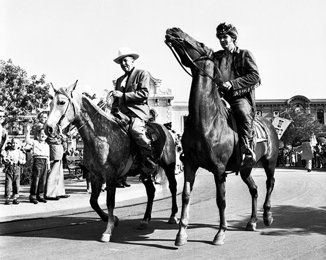 Walt Disney and Fess Parker riding horses at the Disneyland opening
