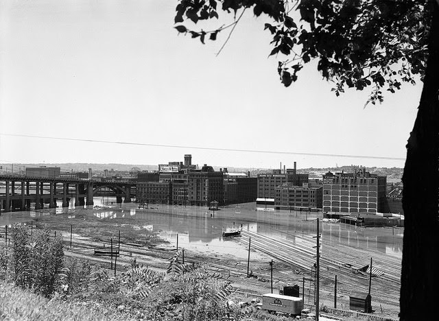 View of brick buildings and railroad tracks submerged in flood waters, 1951