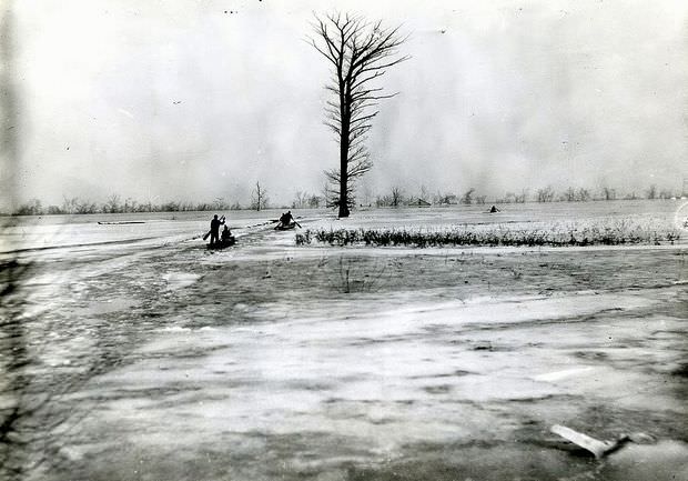 People in boats row through a flooded plain in Southeast Missouri, 1935