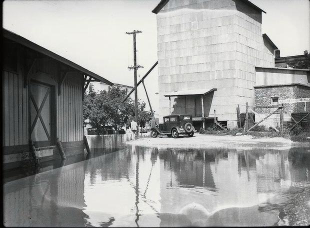 Car sits on an island created by flood waters between buildings near the Osage River in Warsaw, Missouri, 1935