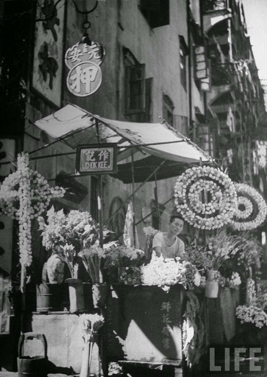 Man selling flowers from a stand on Douglas Street.