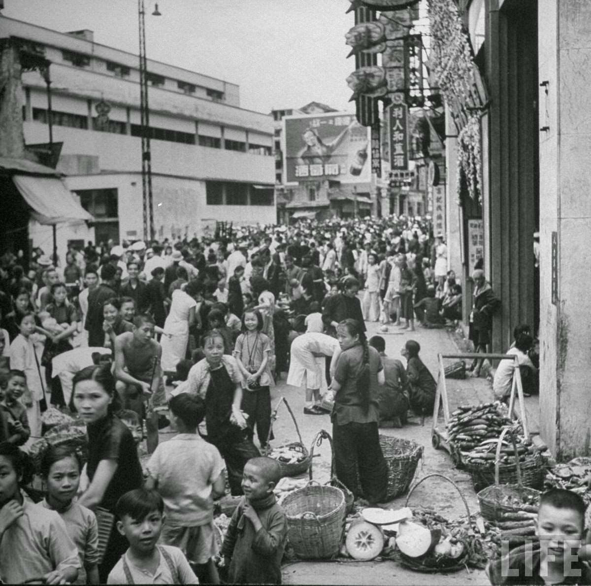 Street vendors and their customers conducting business along Queen's Road.