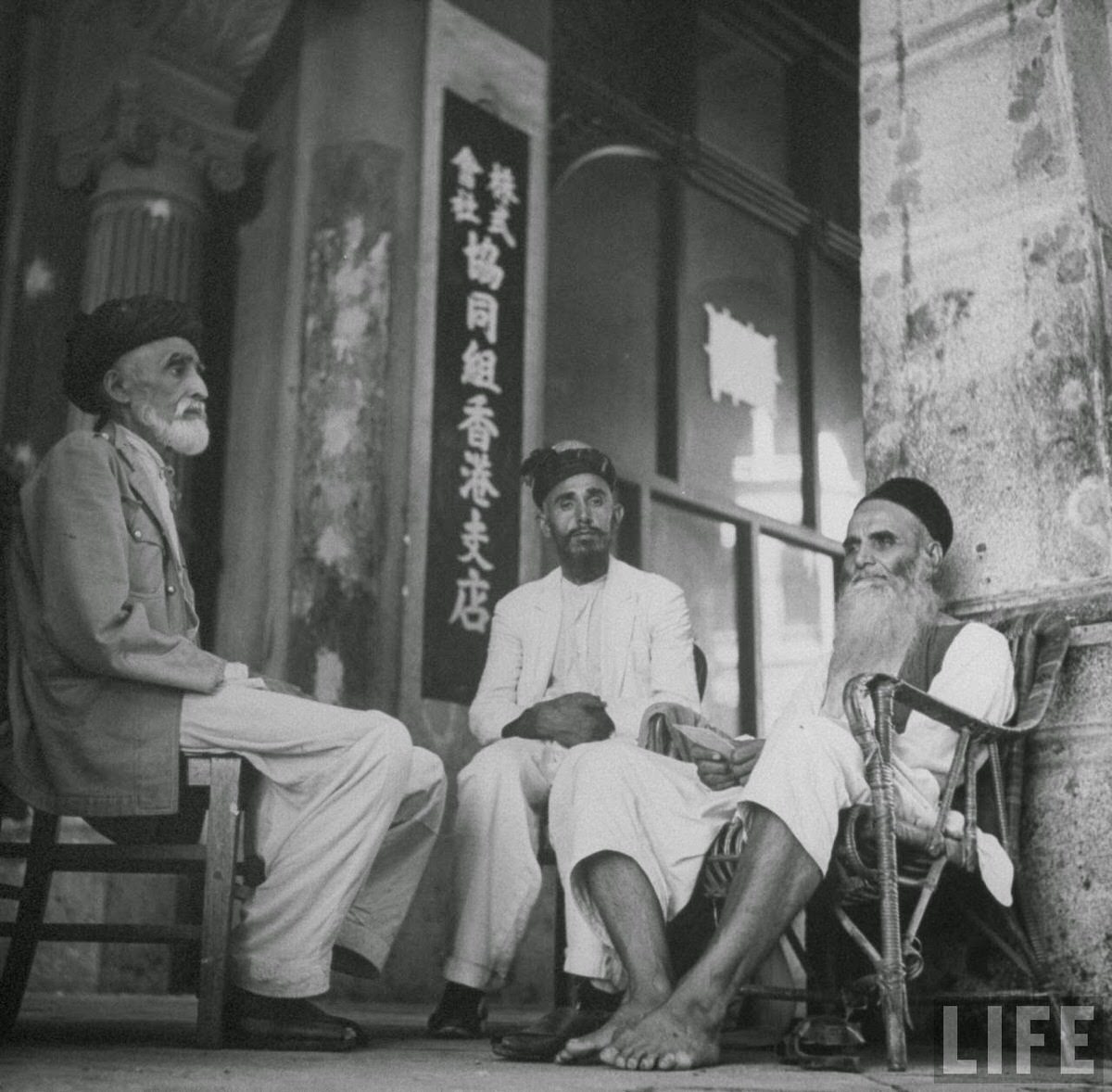 Men from India sitting in front of post office.