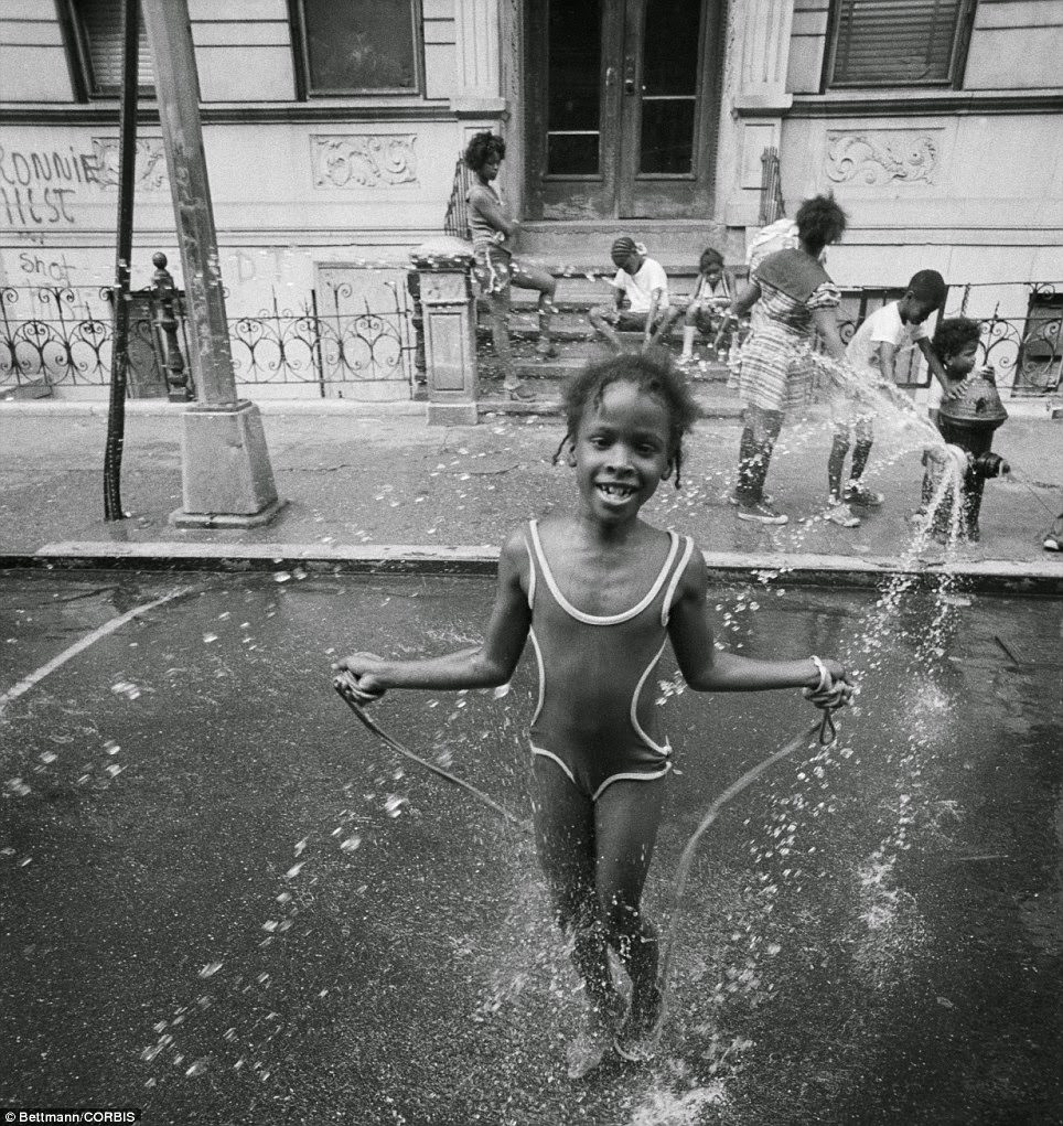 While adults can complain about the heat of summer, many children delight in it; a little girl in Harlem skips away the hours in the refreshing spray of a fire hydrant in the 1950s