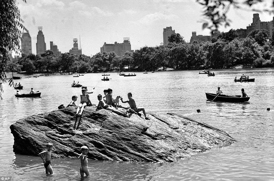 Perched atop a rock in the north end of the Central Park Lake in 1944 are children who take frequent dips while others enjoy boating