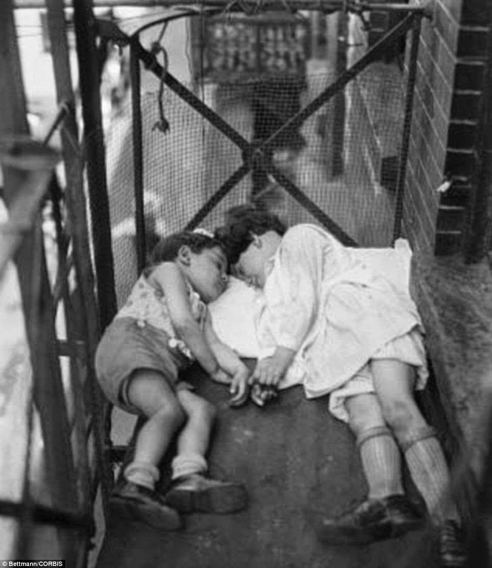 Two children in New York City keep cool during the hot weather by sleeping outside on the fire escape in 1929