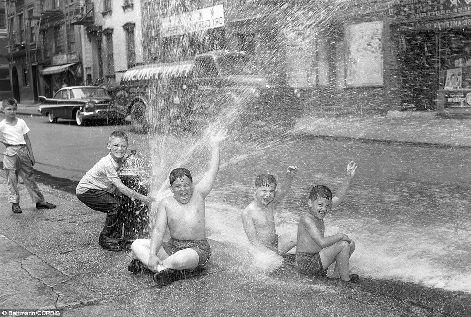 With one youngster manning the hydrant, three boys of New York's super-heated Lower East Side get a cool and refreshing shower as a brief respite in 1957