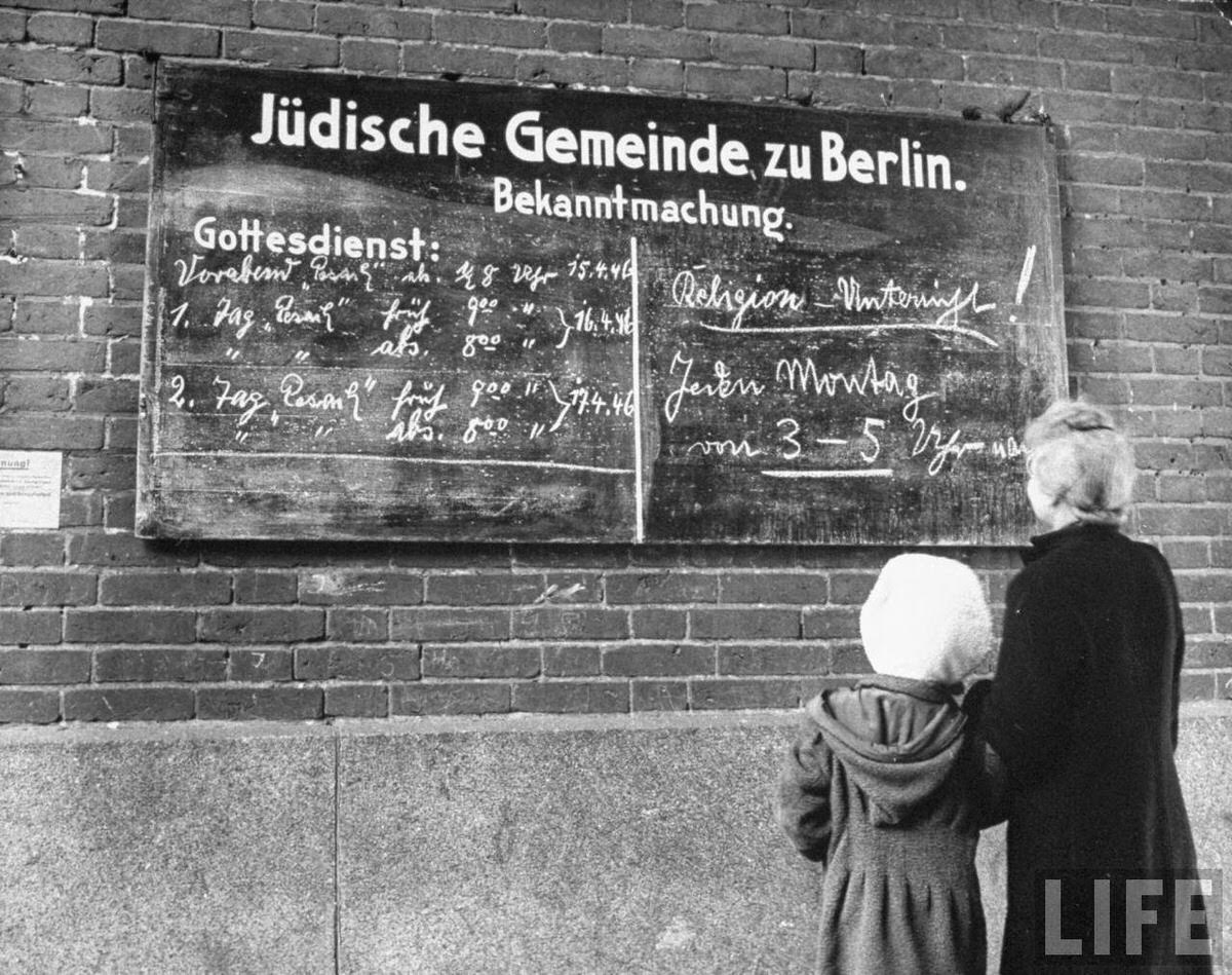A woman and her child reading the bulletin board outside a synagouge during Passover.