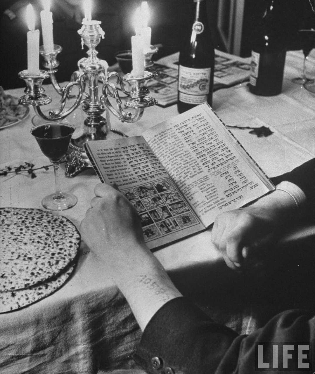 Arm of Gunter Ruschin, with visible concentration camp tattoo, holding book w. question and answers of the exodus of Jews from Egypt during Passover.