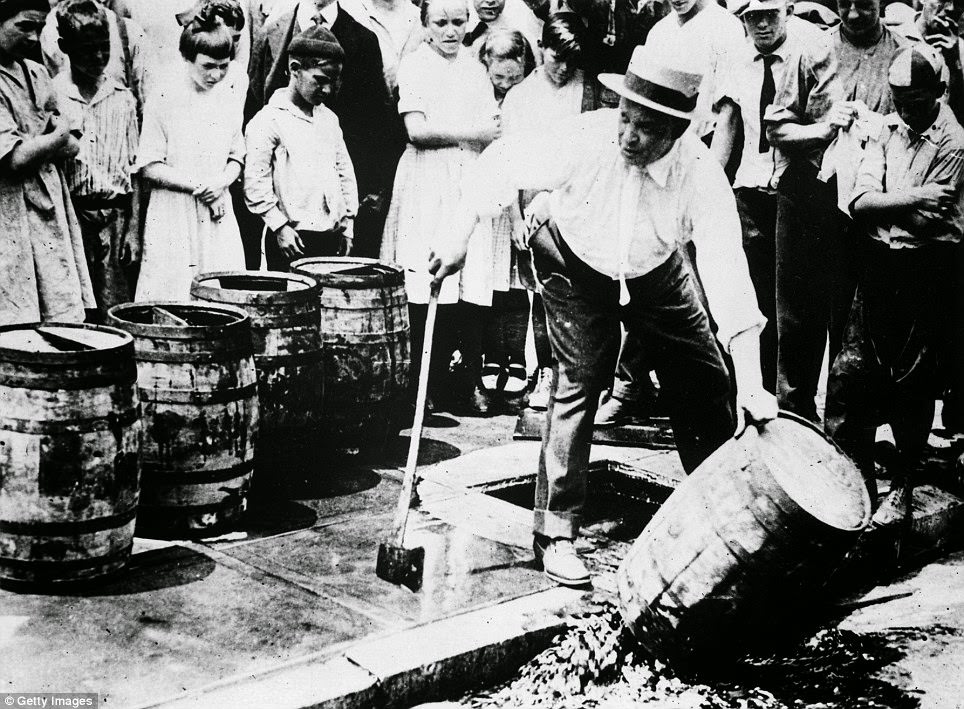 An axe is taken to a barrel as a crowd gathers to watch in about 1920